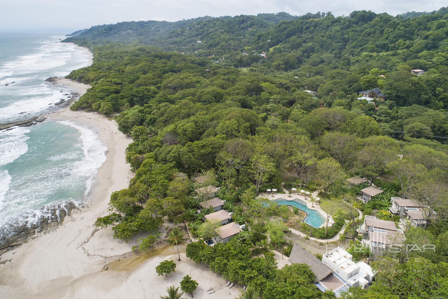 Overhead shot of bungalows on a beach in Costa Rica with the lush green rainforest in the background